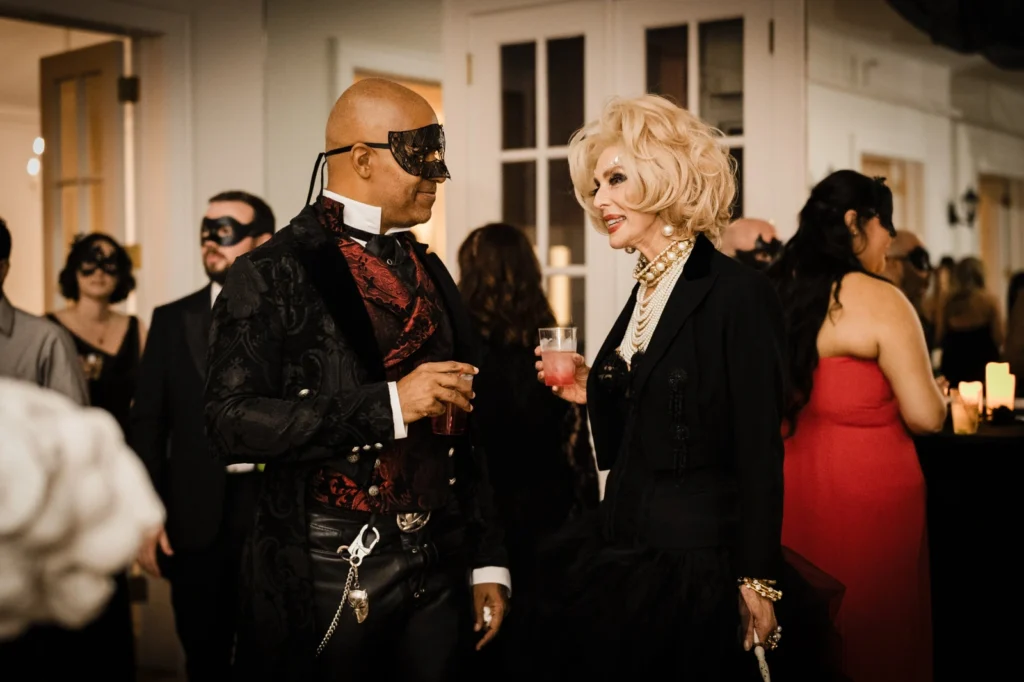 Guests in costume chatting with drinks at the AddamsFest masquerade, James Ward Mansion