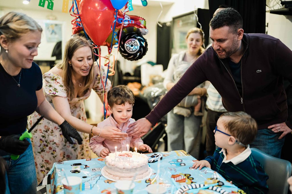 Parents guiding their son toward his lit birthday candles at Crossbar NYC