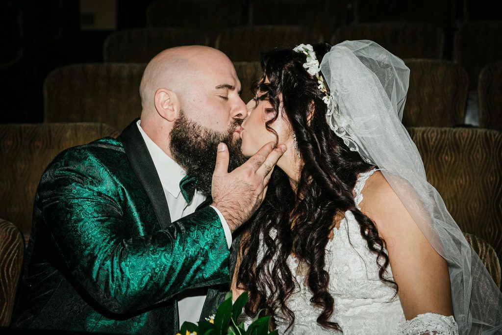 Couple sharing a kiss among theater seats for Scottish Rite wedding photos in Collingswood NJ