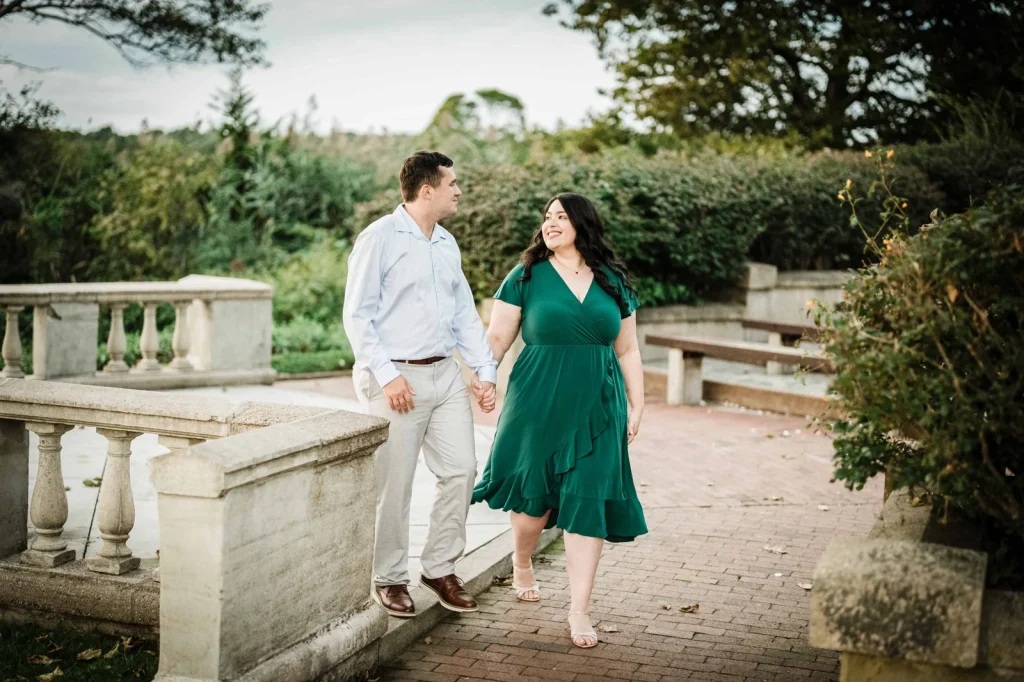 Engaged couple leaning on a stone balustrade above the water at Harkness