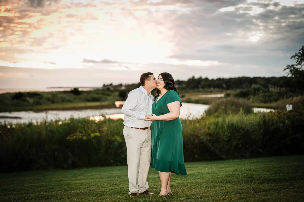 Couple sharing a kiss at sunset above the water at Harkness Memorial State Park