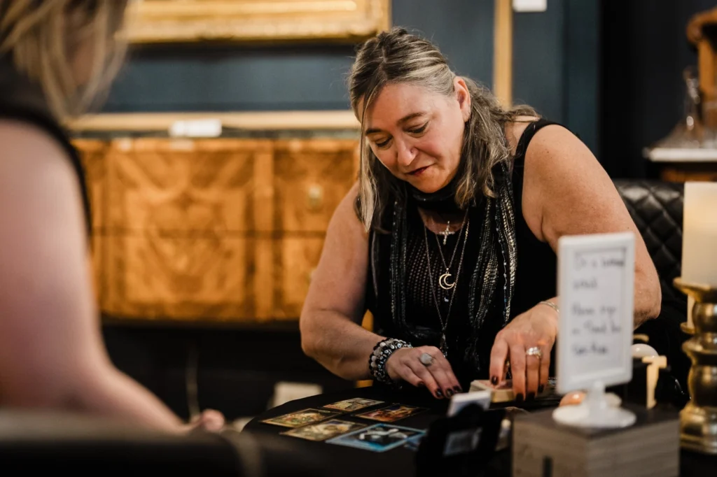 Tarot reader arranging cards at a candlelit table during Morticia's Ball at James Ward Mansion