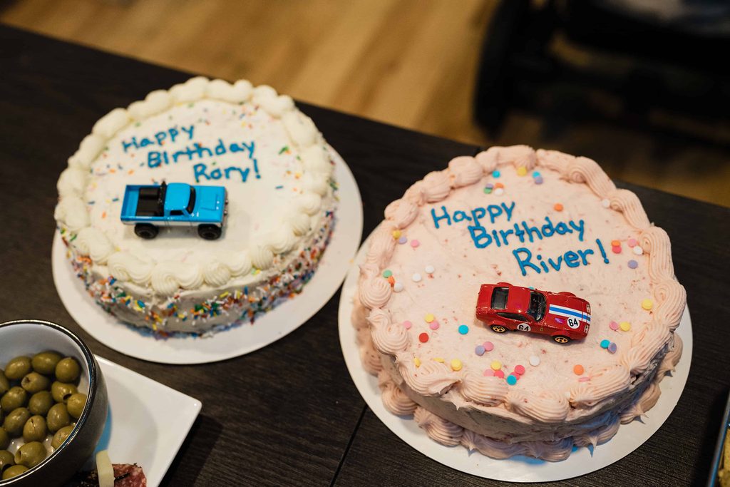Two birthday cakes topped with toy vehicles at a shared birthday party in Manhattan