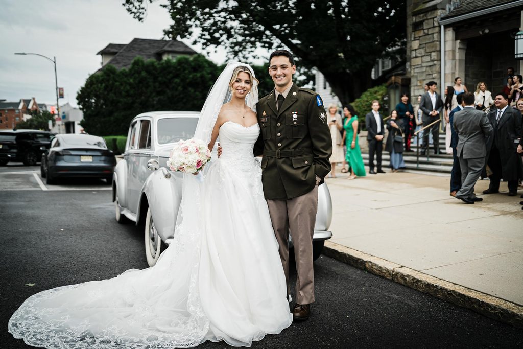 Bride and groom beside a vintage car outside St. Gregory the Great Church in Harrison