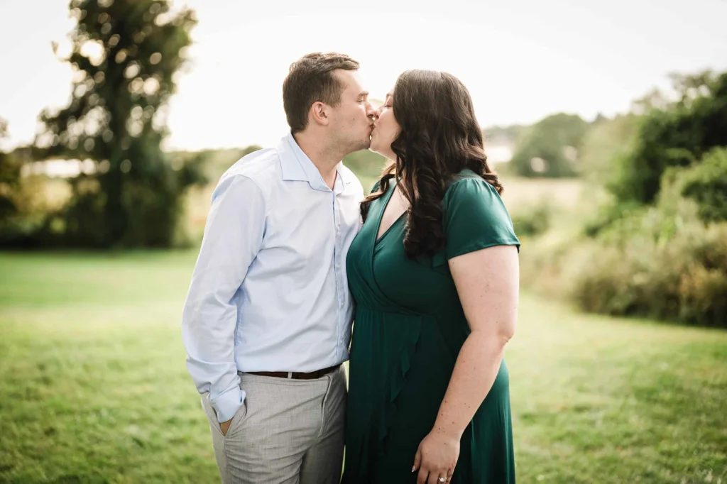 Engaged couple sharing a kiss on an open lawn in Waterford CT